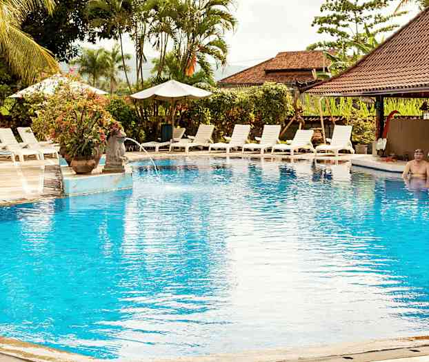 En udendørs pool omgivet af liggestole og parasoller. (AI-genereret tekst)