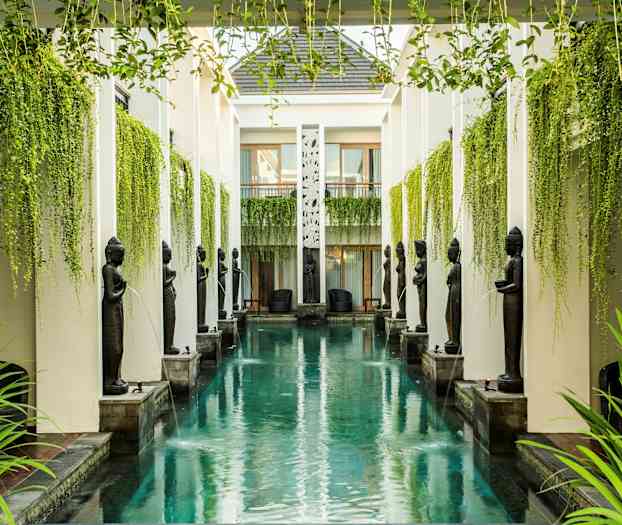 En lang, smal pool omgivet af søjler, statuer og hængende grønt. (AI-genereret tekst)