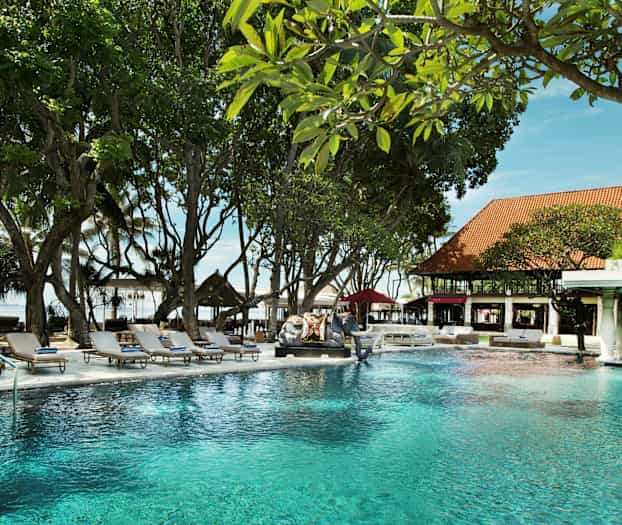 En pool i en have omgivet af liggestole og grønne omgivelser. (AI-genereret tekst)