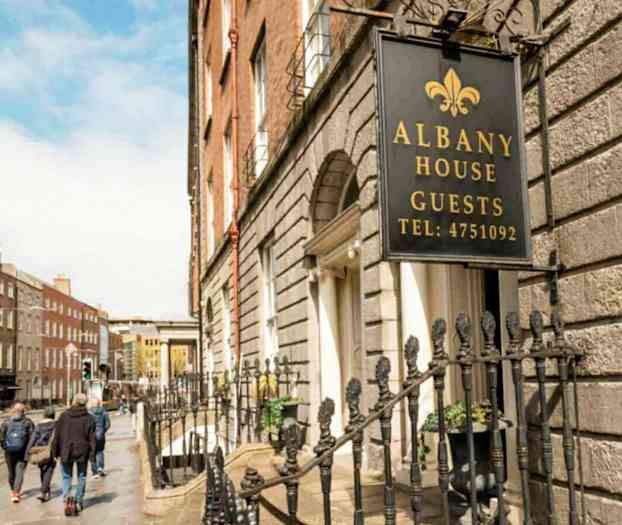 Skilt med teksten Albany House Guests ved en husfacade. (AI-genereret tekst)