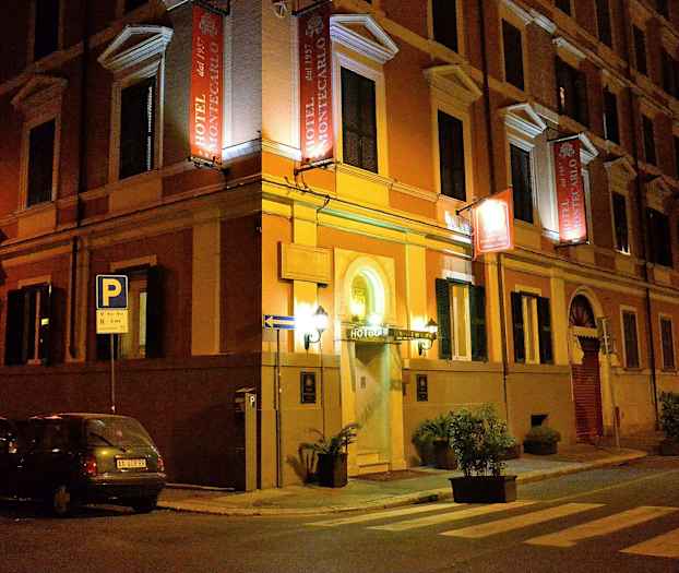 Et hotel ved navn Hotel Montecarlo er beliggende på et gadehjørne om aftenen. (AI-genereret tekst)