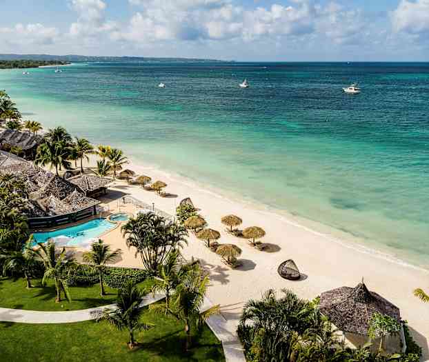 En strand med parasoller og et resort med swimmingpool. (AI-genereret tekst)