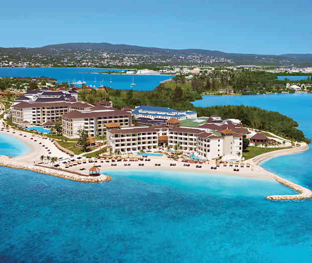 Et feriested ved havet med strande og swimmingpools, omgivet af grønt og blåt vand. (AI-genereret tekst)