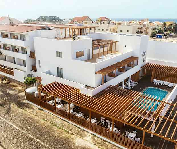 Lejlighedsbygning med hvid facade, trædetaljer og udendørs pool. (AI-genereret tekst)