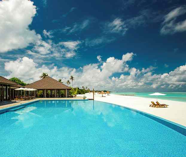 En luksuriøs resort med pool ved siden af en hvid sandstrand. (AI-genereret tekst)