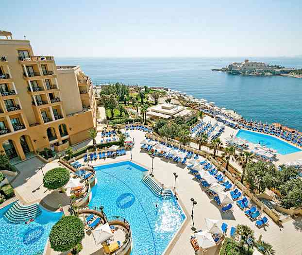 Et hotelanlæg med pools, liggestole og parasoller samt havudsigt. (AI-genereret tekst)