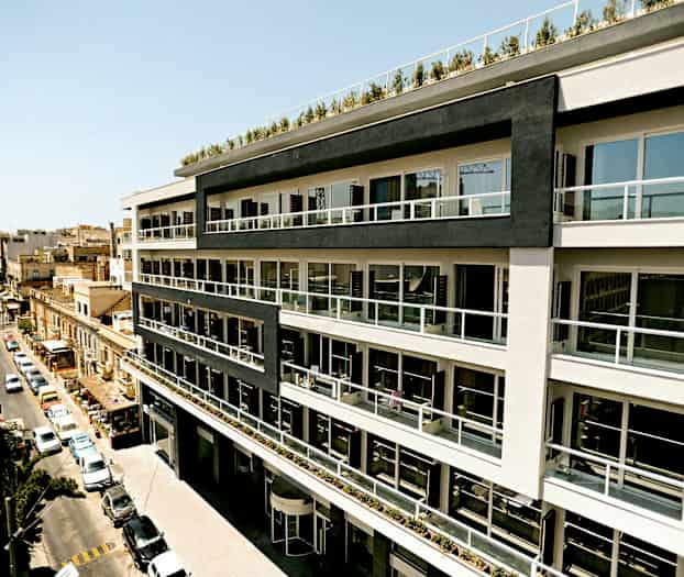 En fler-etagers bygning med moderne altaner langs facaden, beliggende ved en bygade. (AI-genereret tekst)