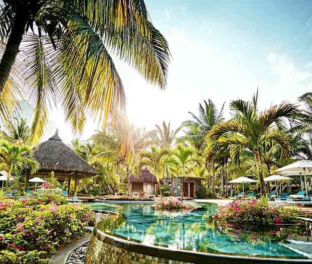 En pool omgivet af palmer og vegetation i et tropisk område. (AI-genereret tekst)