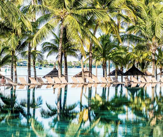 Solsenge og palmer ved en pool i tropisk miljø. (AI-genereret tekst)