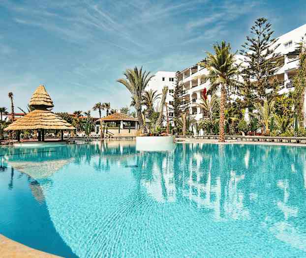 En pool med parasoller og omkringliggende palmer. (AI-genereret tekst)