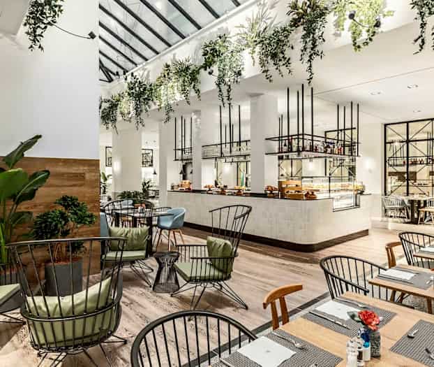 Interiør af en lys og moderne restaurant med planter og elegant møblering. (AI-genereret tekst)
