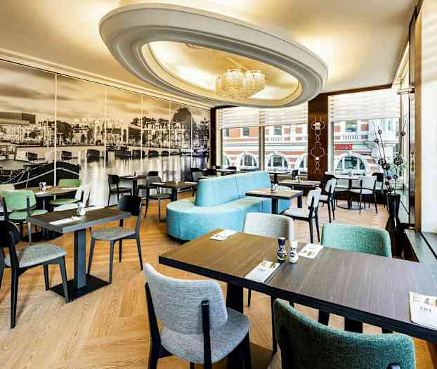 En restaurantindretning med moderne møbler og stort fototapet af et bybillede på væggen. (AI-genereret tekst)