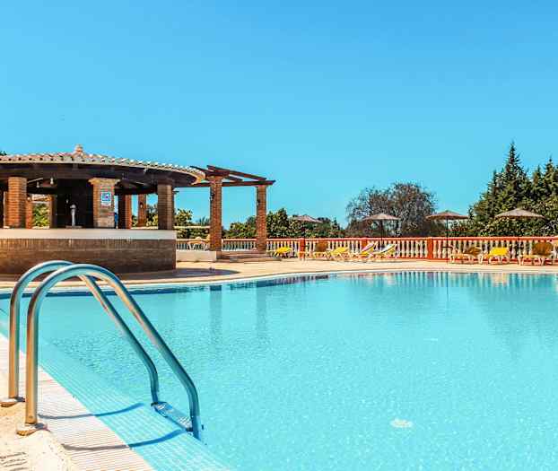 Poolområde med solsenge, parasoller og en bar ved kanten. (AI-genereret tekst)