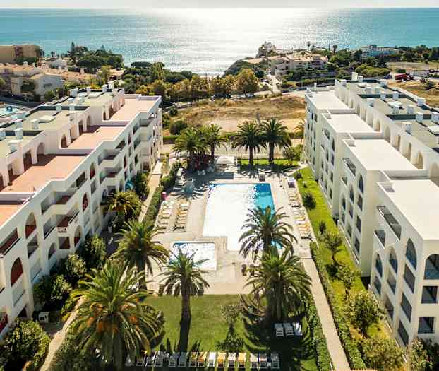 Luftfoto af hotel med poolområde og udsigt over havet. (AI-genereret tekst)