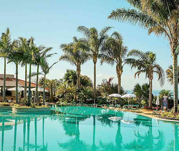 Udendørs pool omgivet af palmer og liggestole. (AI-genereret tekst)