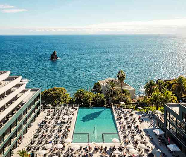 Hotel ved havet med en pool og liggestole. (AI-genereret tekst)