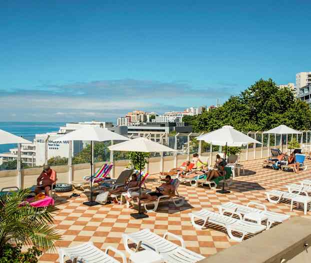 Solterrasse med liggestole og parasoller, med udsigt over havet. (AI-genereret tekst)