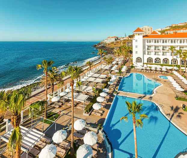 Hotel med poolområde og udsigt over havet. (AI-genereret tekst)