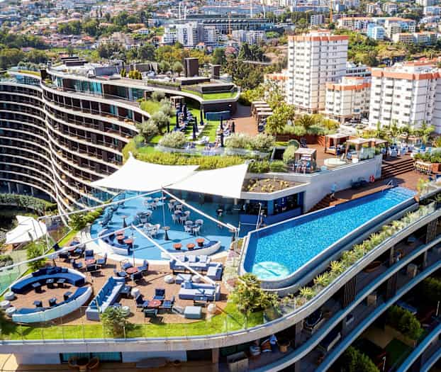 Hotelkompleks med terrasse, pool og siddeområder. (AI-genereret tekst)