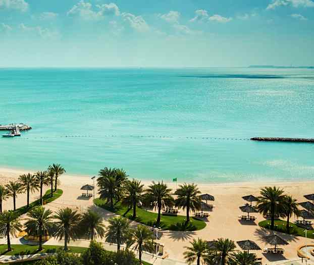 Sandstrand med hvide parasoller, palmetræer og turkis vand. (AI-genereret tekst)