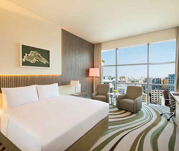 Et moderne hotelværelse med en stor seng og to stole foran et vindue. (AI-genereret tekst)