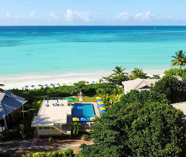 Et feriested ved en strand med turkisblåt vand og omkringliggende vegetation. (AI-genereret tekst)