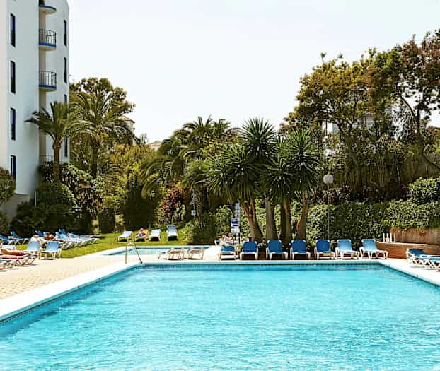 En pool omgivet af liggestole og træer. (AI-genereret tekst)