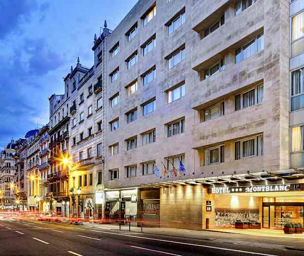 En bygade med et hotel kaldet Montblanc ses på højre side, med flere façader og aftenbelysning. (AI-genereret tekst)