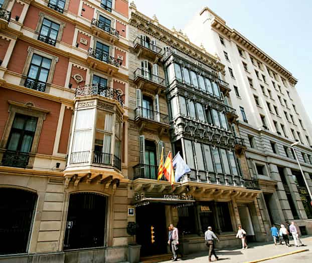 Et billede af facaden af flere historiske bygninger med forskellige arkitektoniske stilarter og flag, der hænger udenfor. (AI-genereret tekst)