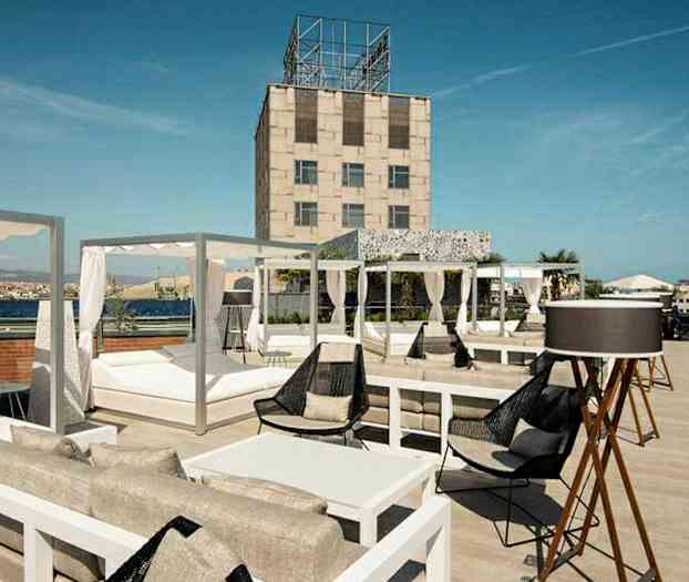 En tagterrasse med siddegrupper, liggestole og udsigt over omgivelserne. (AI-genereret tekst)