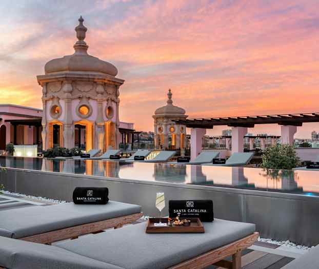 Udsigt over tagpool med liggestole og dekorative kupler i solnedgang. (AI-genereret tekst)