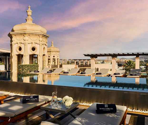 Tagpool med solsenge og udsigt over byen. Ornamenteret arkitektur i baggrunden. (AI-genereret tekst)