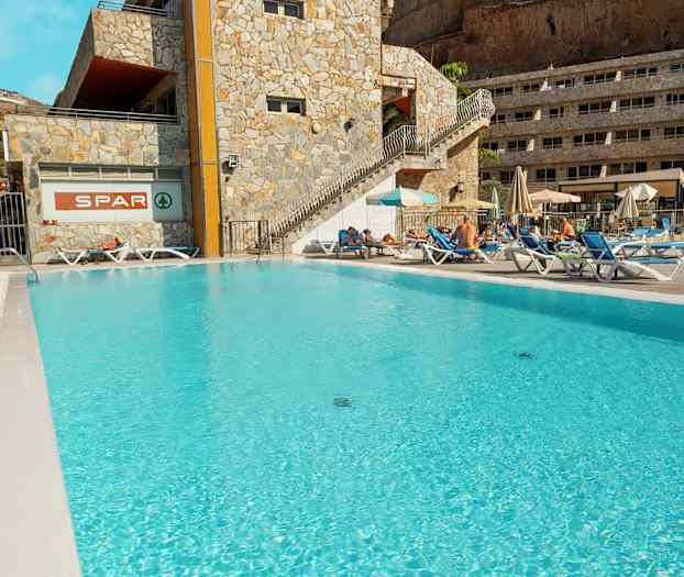 Udendørs pool ved hotel med liggestole og parasoller. (AI-genereret tekst)