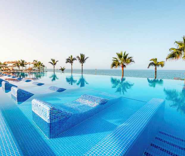 En infinitypool med udsigt over havet og omkringliggende palmer. (AI-genereret tekst)