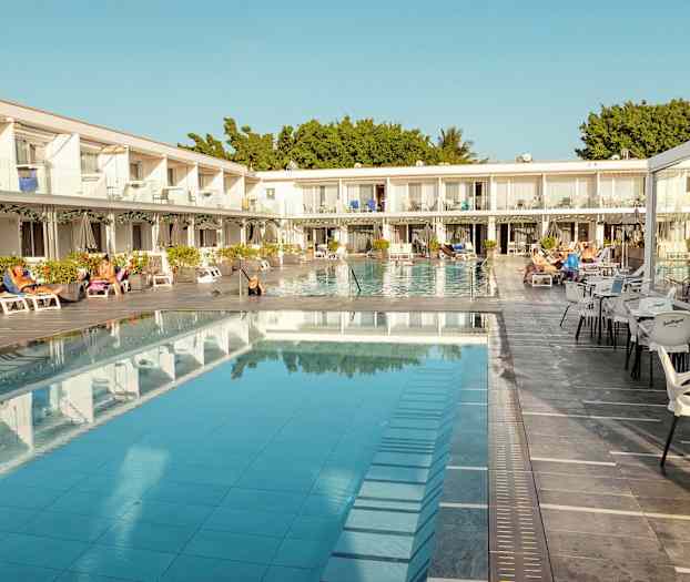 Hotelområde med pool, liggestole og siddepladser. (AI-genereret tekst)