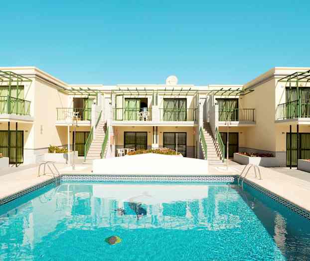 En pool foran en bygning med altaner og grønne detaljer. (AI-genereret tekst)