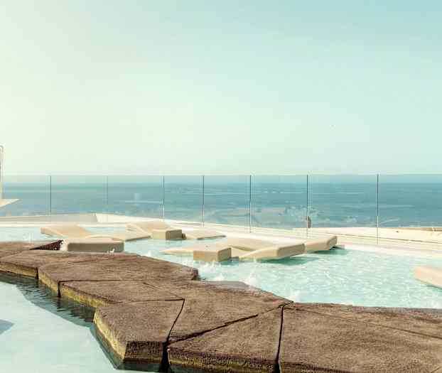 En infinitypool med liggestole og udsigt over havet. (AI-genereret tekst)