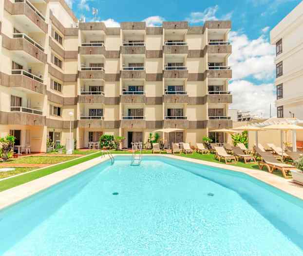 Hotelbygning med pool foran. (AI-genereret tekst)