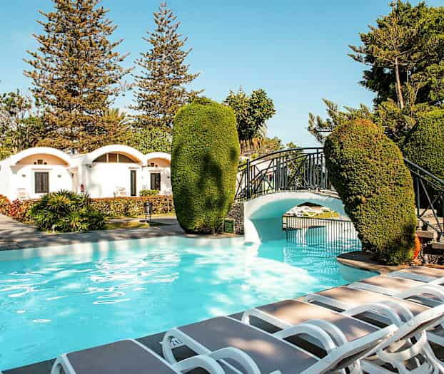 Udendørspool med rummeligt område, liggestole og en lille bro i haven. (AI-genereret tekst)