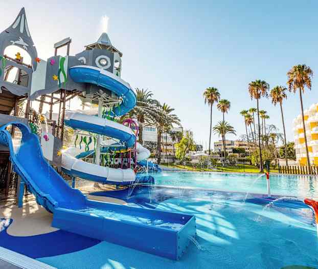 En vandpark med rutsjebaner og legeudstyr, omgivet af palmer og hotelbygninger. (AI-genereret tekst)