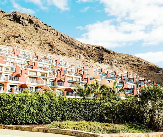 Flere rækkehuse med altaner på en skråning. (AI-genereret tekst)