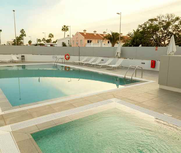 En udendørs swimmingpool med liggestole ved siden af. (AI-genereret tekst)
