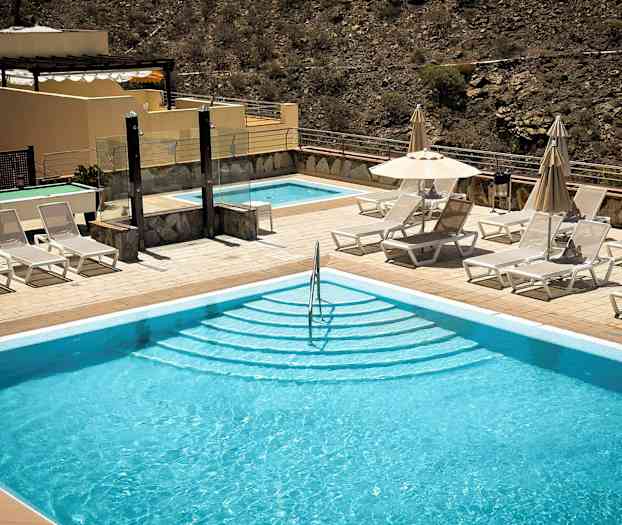 Udendørs pool med liggestole og parasoller ved siden af. (AI-genereret tekst)