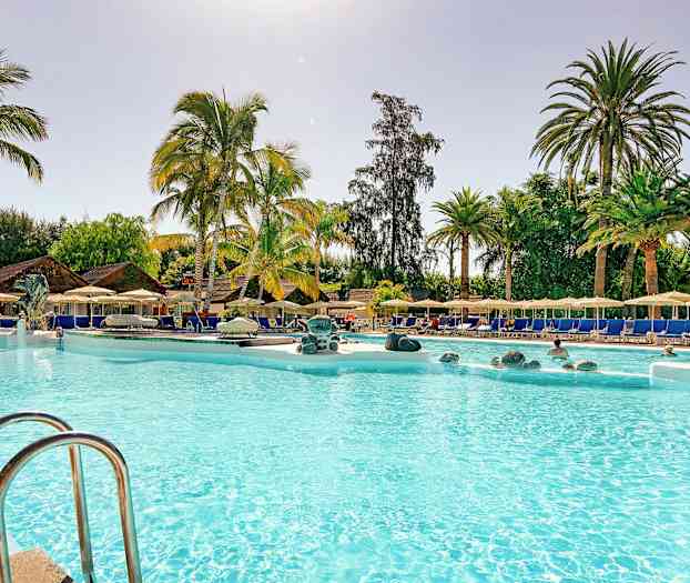 Poolområde med palmer, liggestole og parasoller. (AI-genereret tekst)