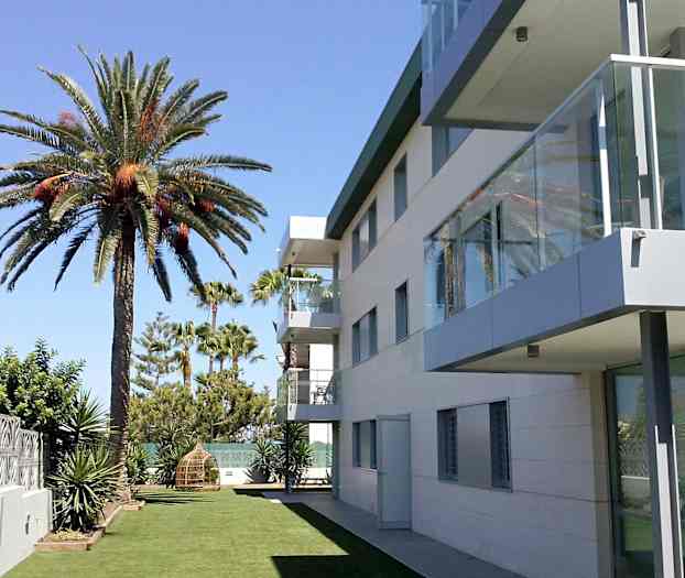 Moderne bygning ved siden af en græsplæne med palmer. (AI-genereret tekst)