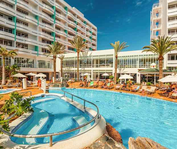 Hotelområde med pool, liggestole og bygning i baggrunden. (AI-genereret tekst)