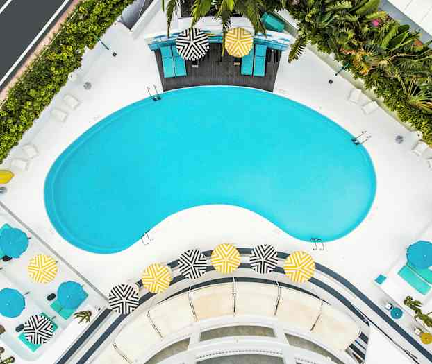 Luftfoto af et poolområde med liggestole og farverige parasoller. (AI-genereret tekst)