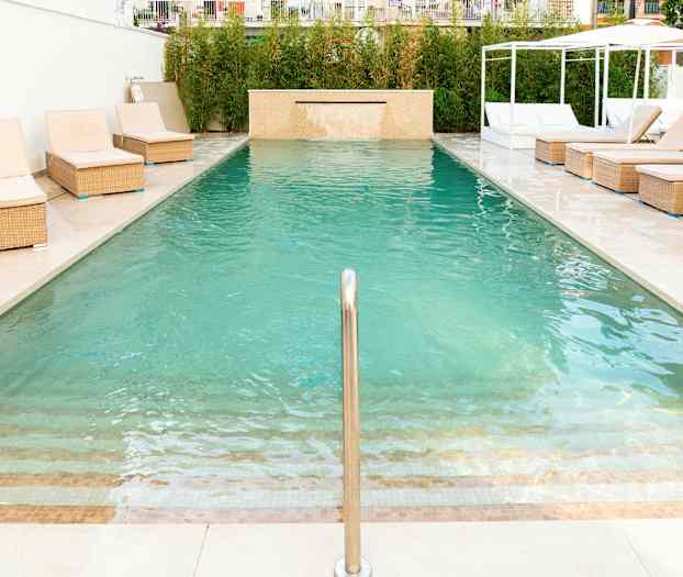 En swimmingpool med liggestole ved kanten. (AI-genereret tekst)