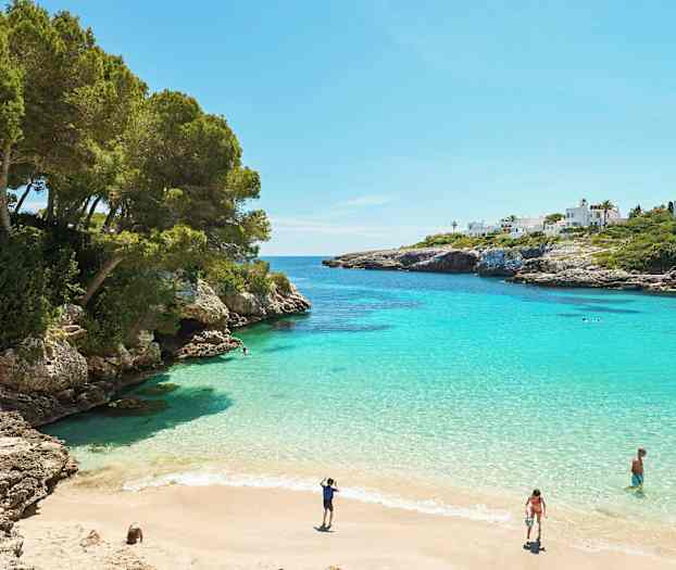 En bugt med turkis vand, sandstrand og omkringliggende klipper. (AI-genereret tekst)