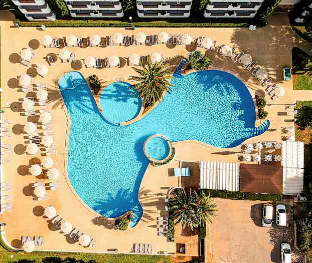 Luftfoto af en pool med liggestole og parasoller omkring. (AI-genereret tekst)